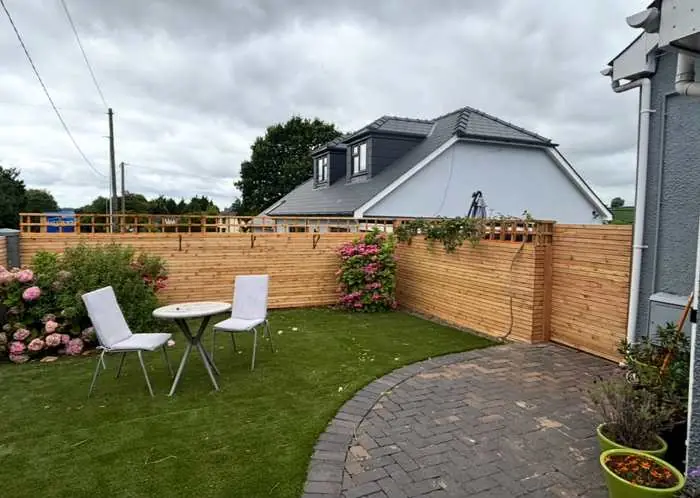Horizontal slatted garden fence with trellis top, artificial lawn and block paved patio