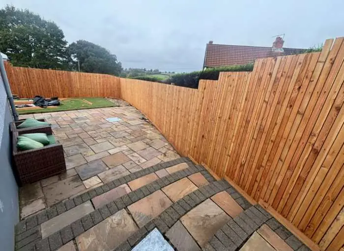 Stepped timber fencing beside a sandstone patio