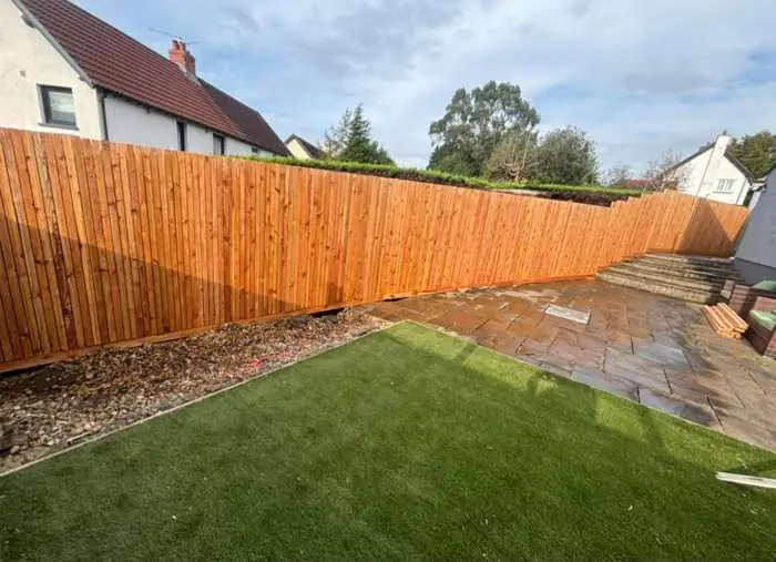 New timber fence on a sloped garden with artificial grass and Indian sandstone patio